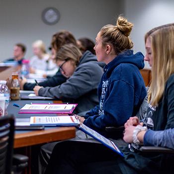 Students listening and taking notes during a lecture.